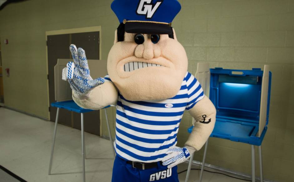GVSU mascot Louie the Laker showing the Anchor Up hand symbol at a polling location